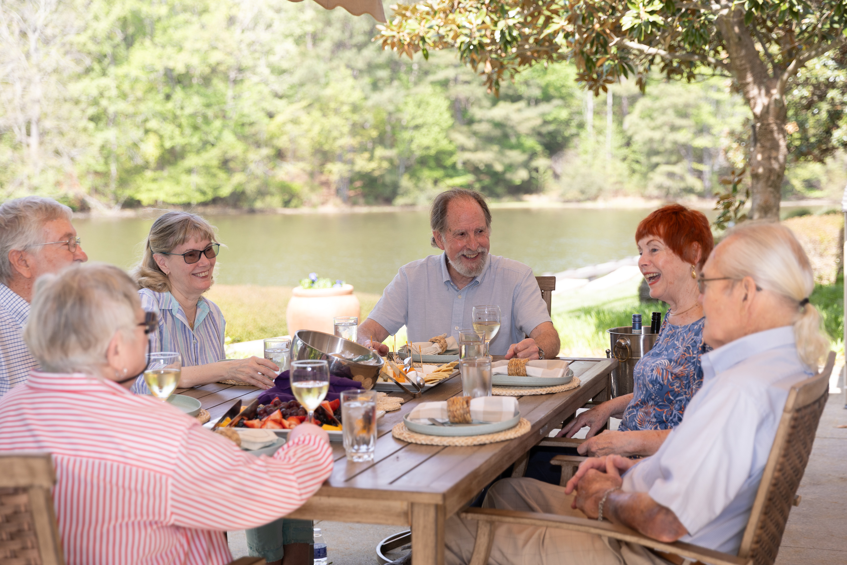 Seniors enjoying outdoor lunch by lakeside table