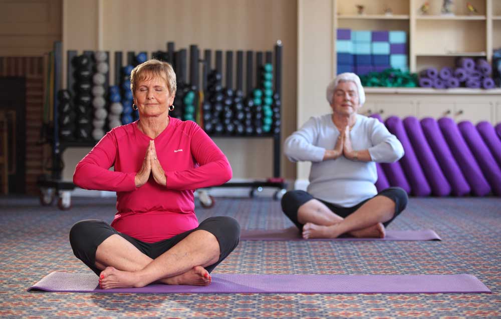 Two ladies practice yoga in our fitness center