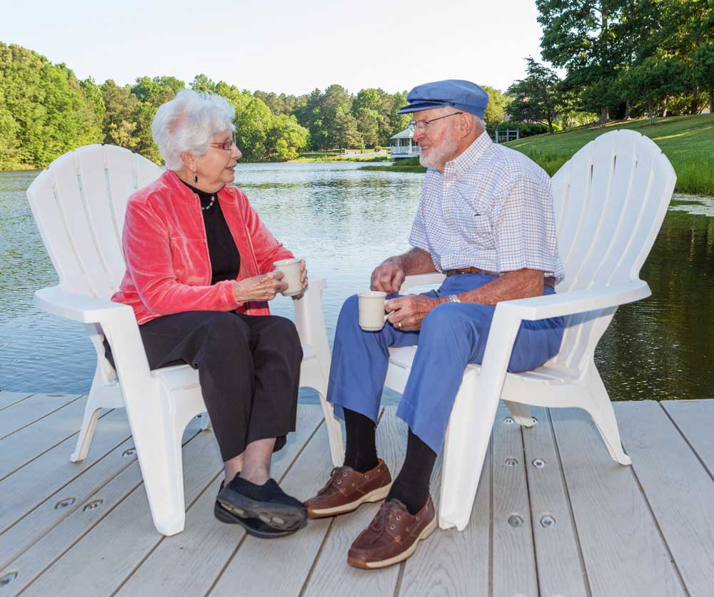 A woman and a man enjoy a pleasant conversation on the dock at the lake