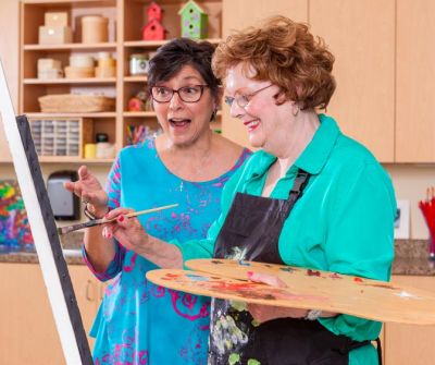 A resident paints with assistance from Maria