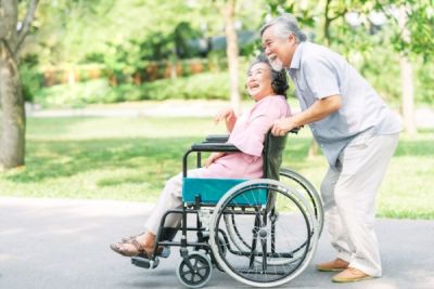 senior man pushing senior woman in wheelchair