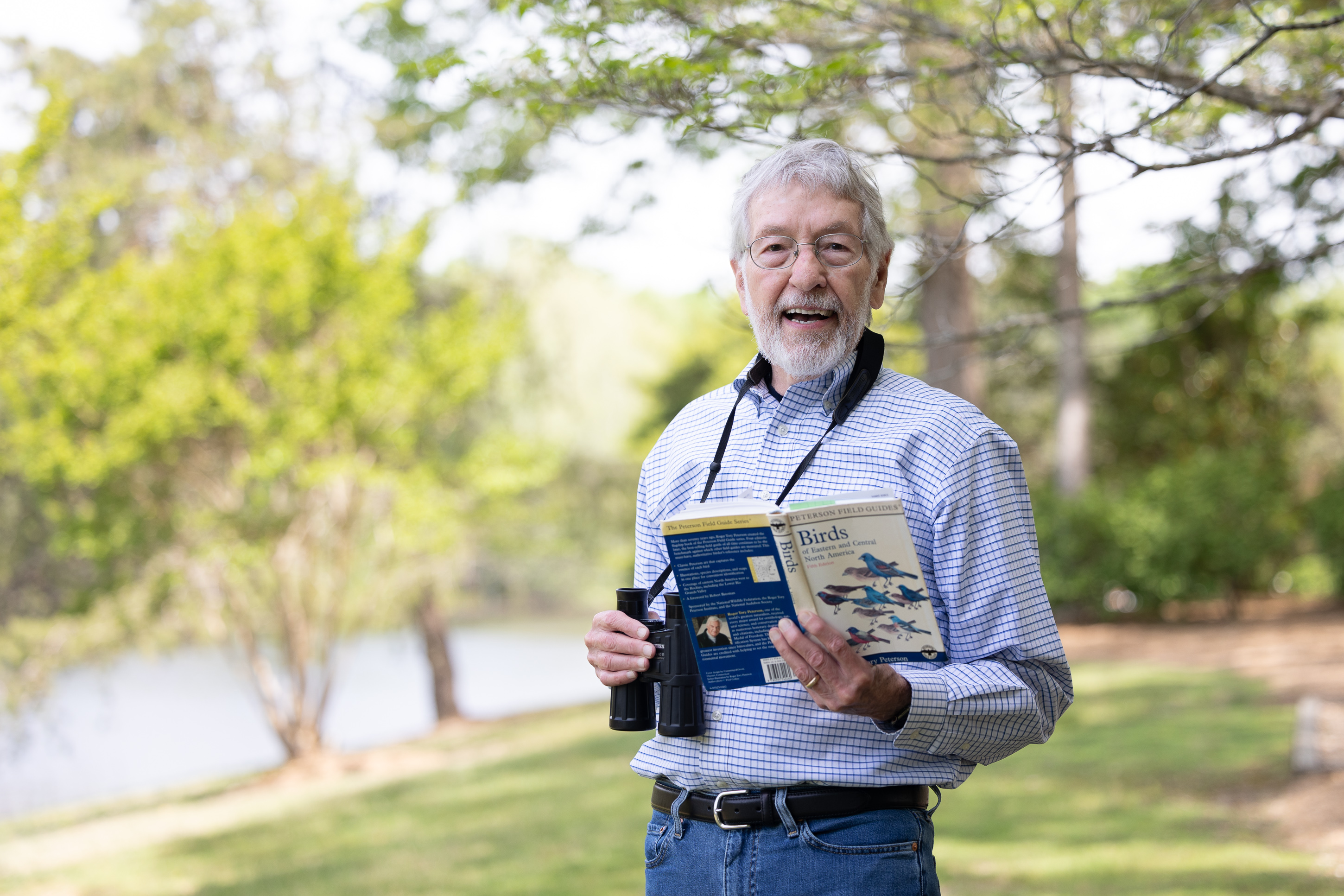Man birdwatching with binoculars and field guide outdoors