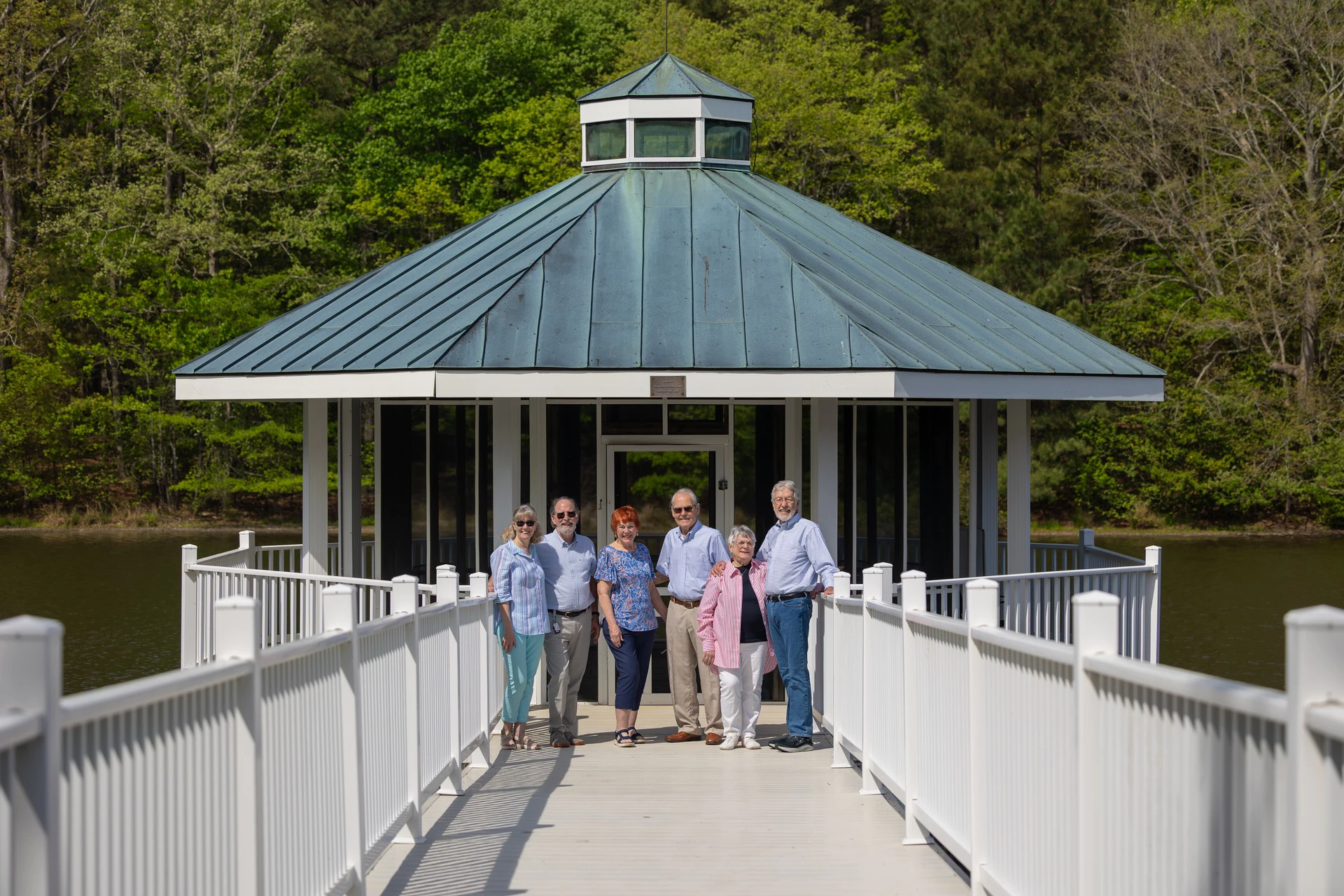 Six adults on dock before lakeside gazebo