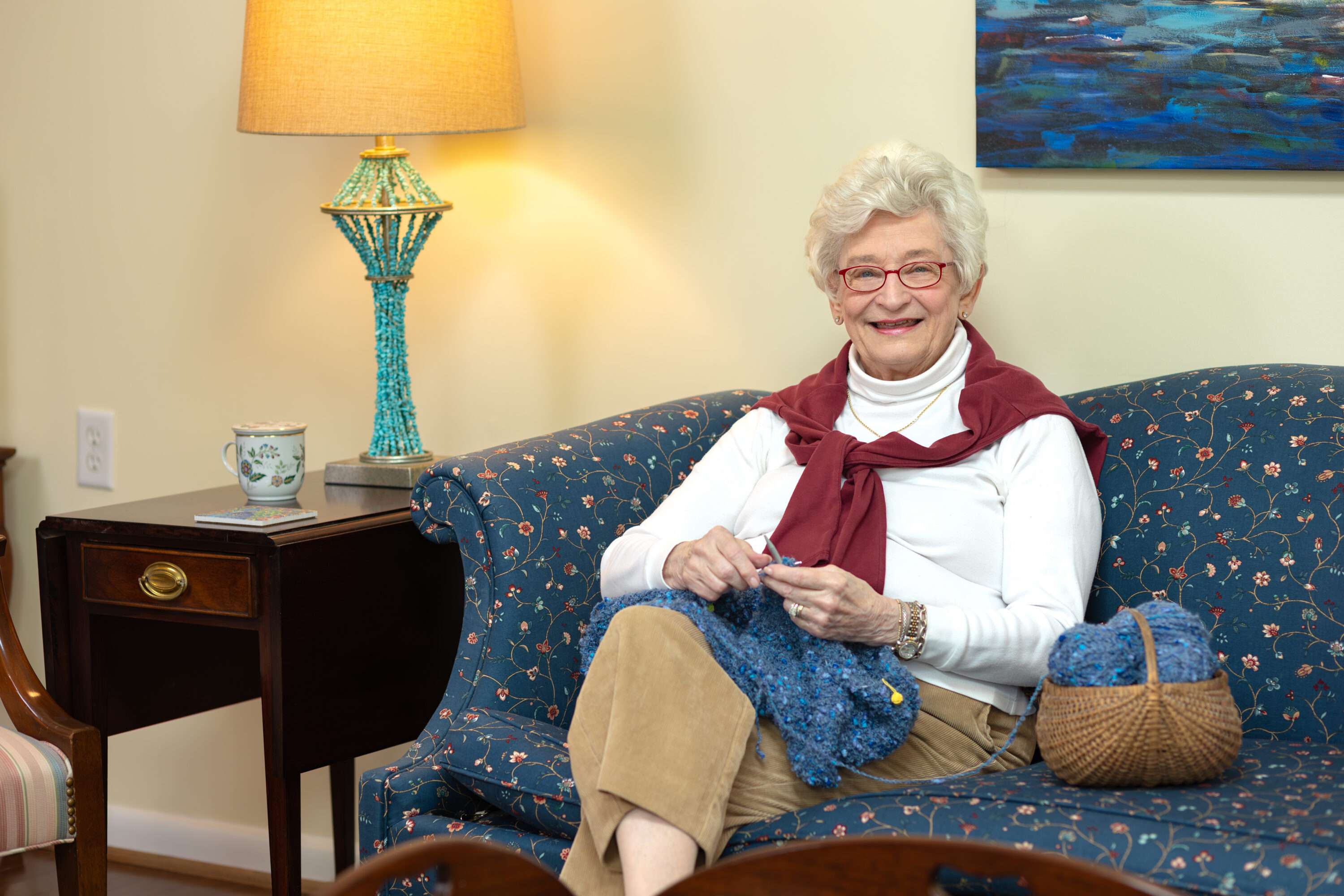 Elderly woman knitting on living room couch