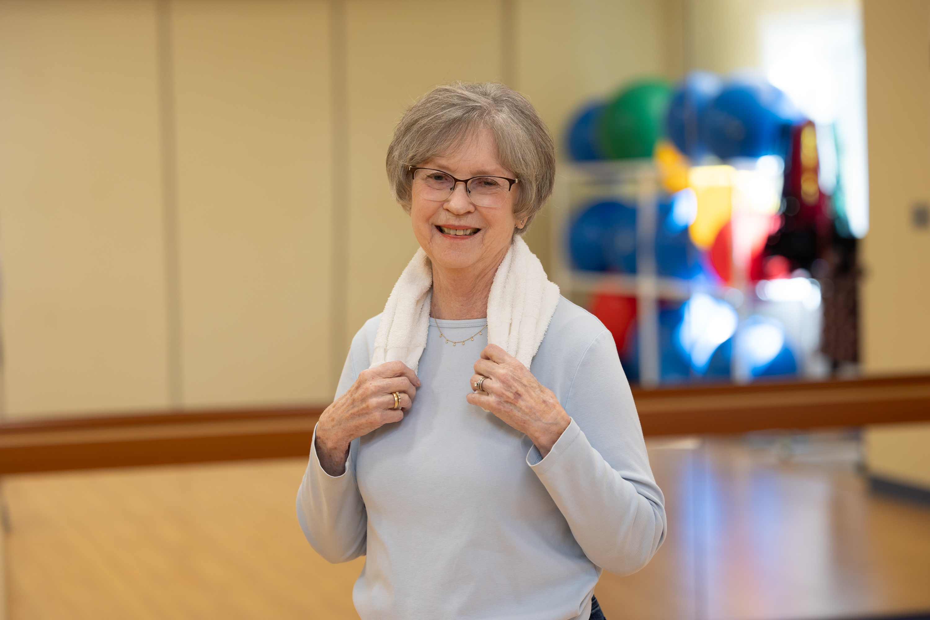 Smiling senior woman with towel in fitness center