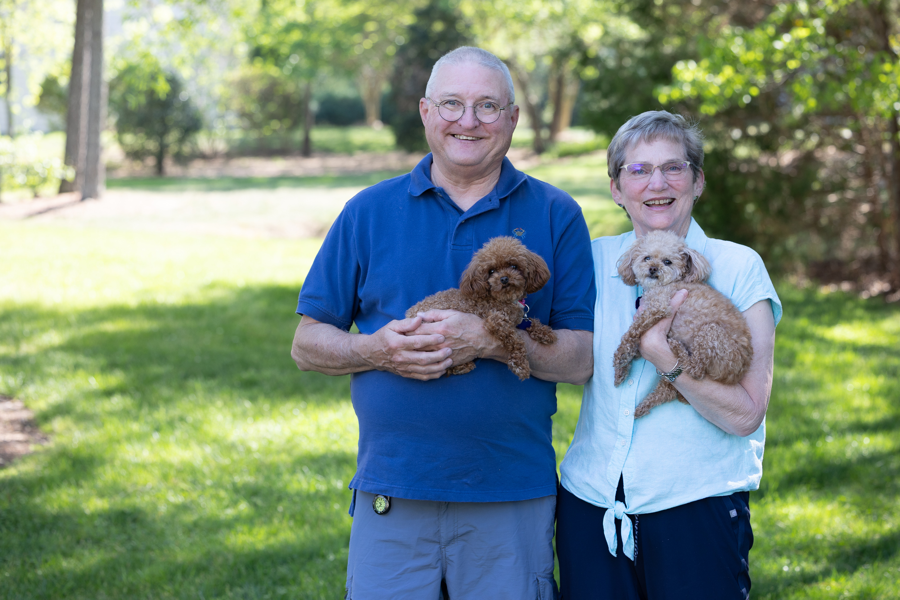 Smiling couple holding small dogs in park
