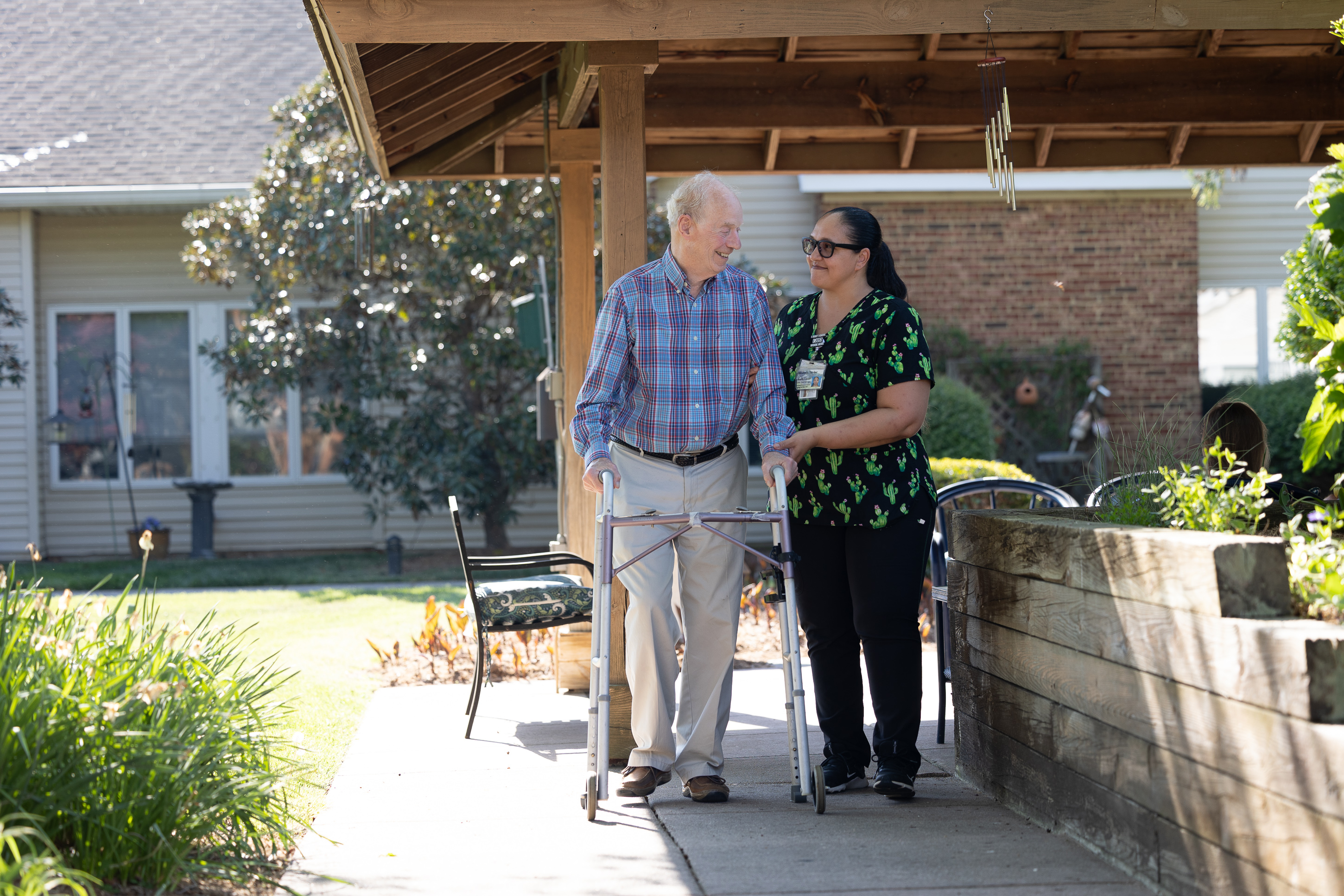 Caregiver assisting elderly man with walker outdoors