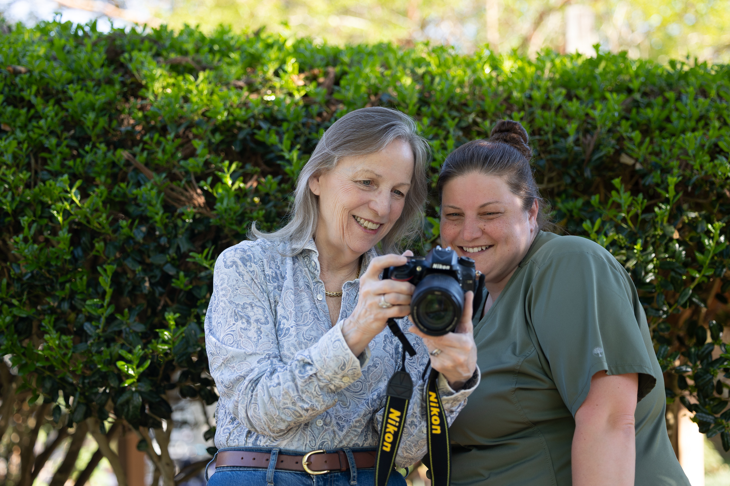 Two women reviewing photos on camera outdoors