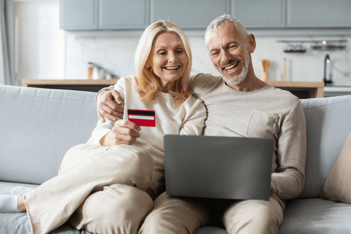 Elderly couple enjoying finding reliable financial resources together at home on a cozy sofa