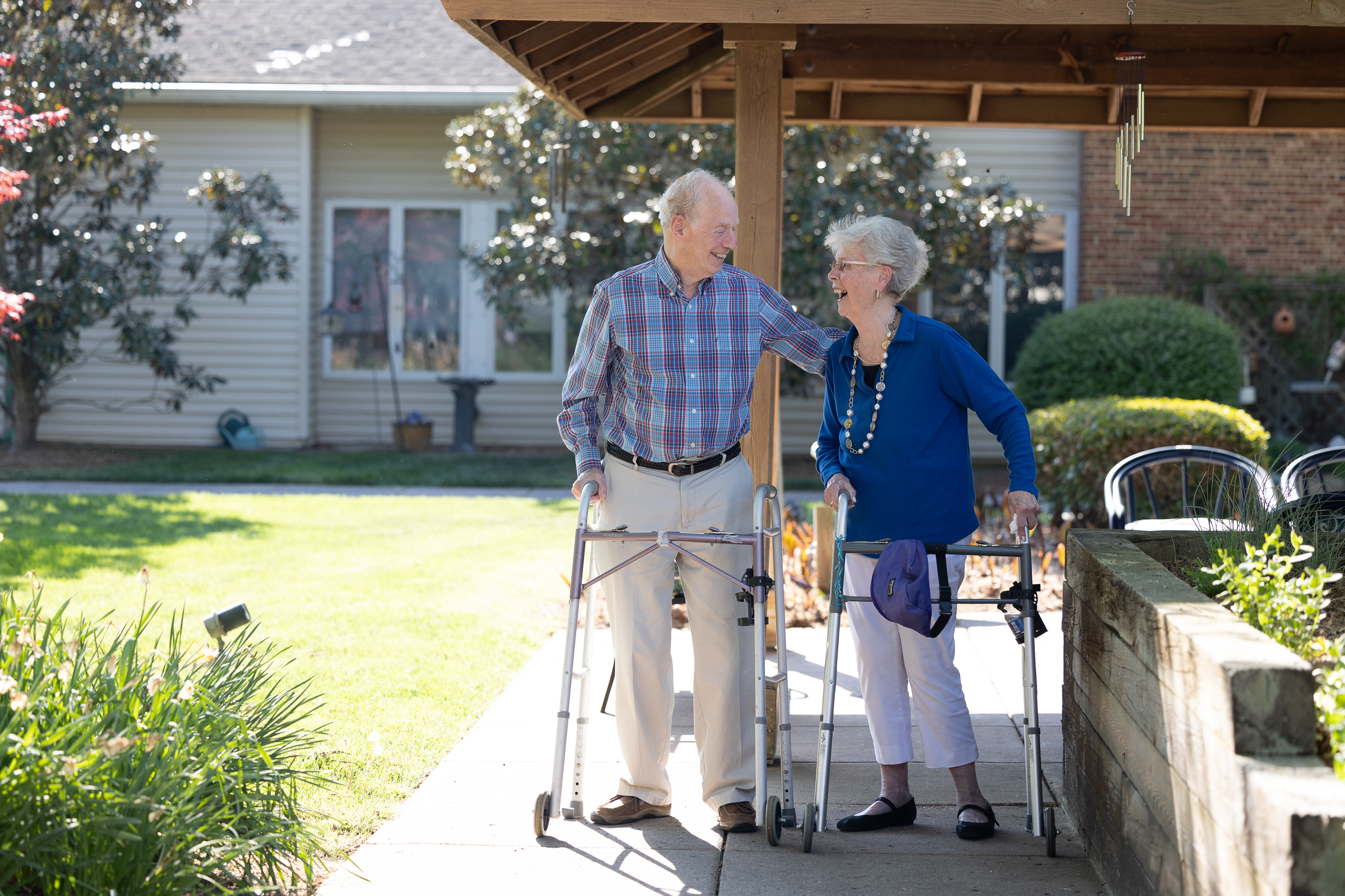 Elderly couple with walkers smiling outdoors