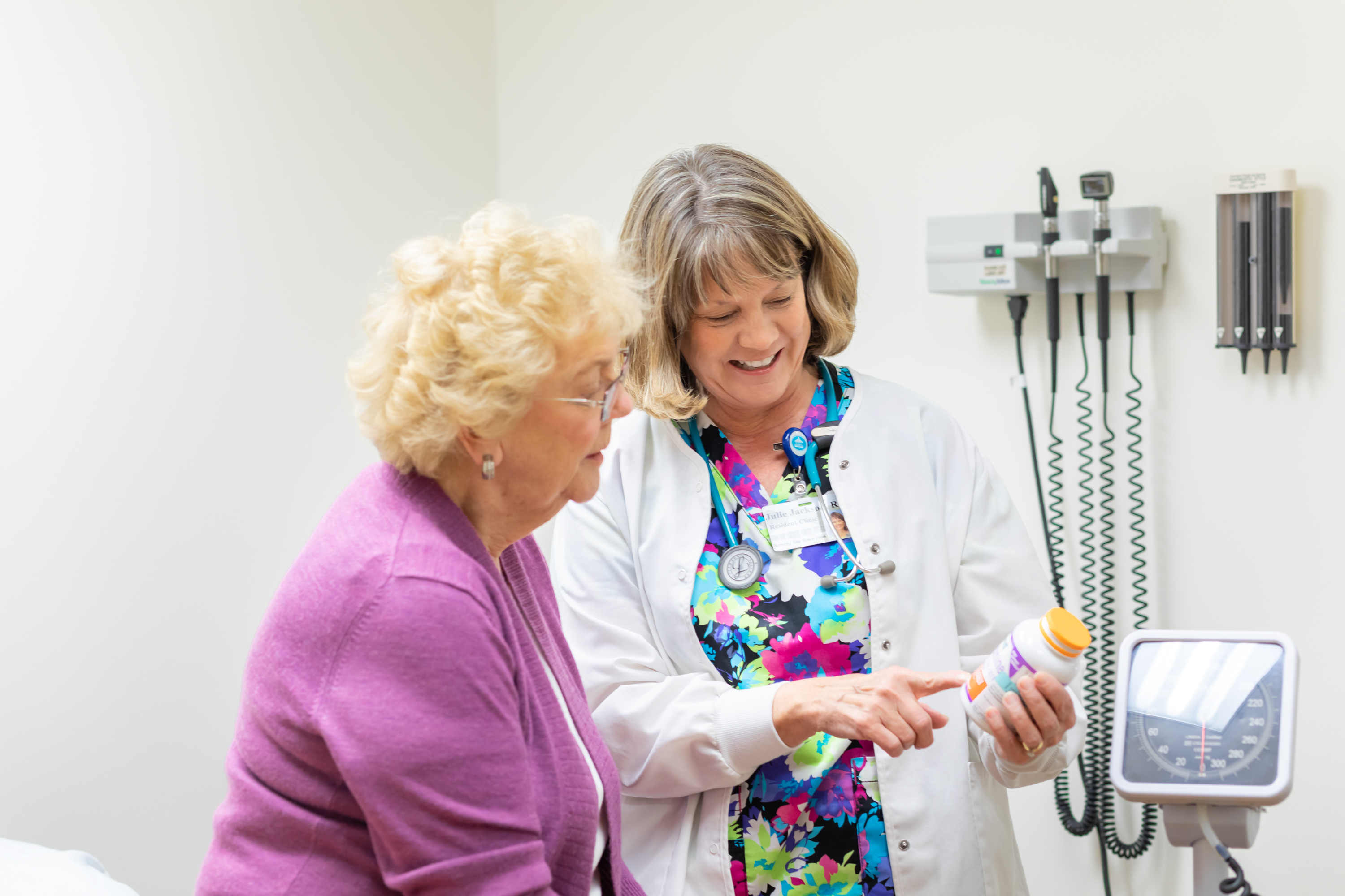 Nurse reviewing medication with elderly patient in exam room
