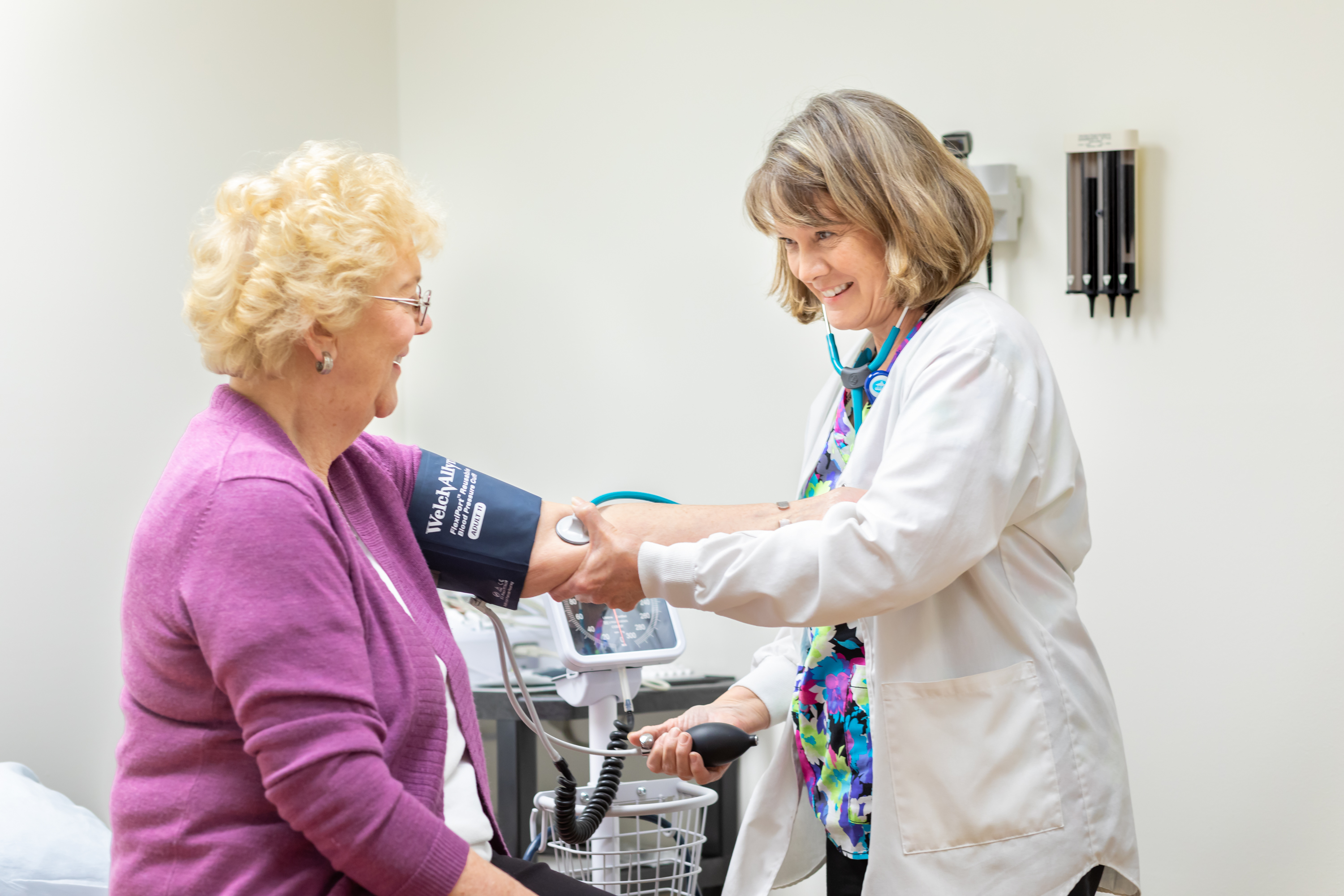 Doctor checking elderly woman's blood pressure