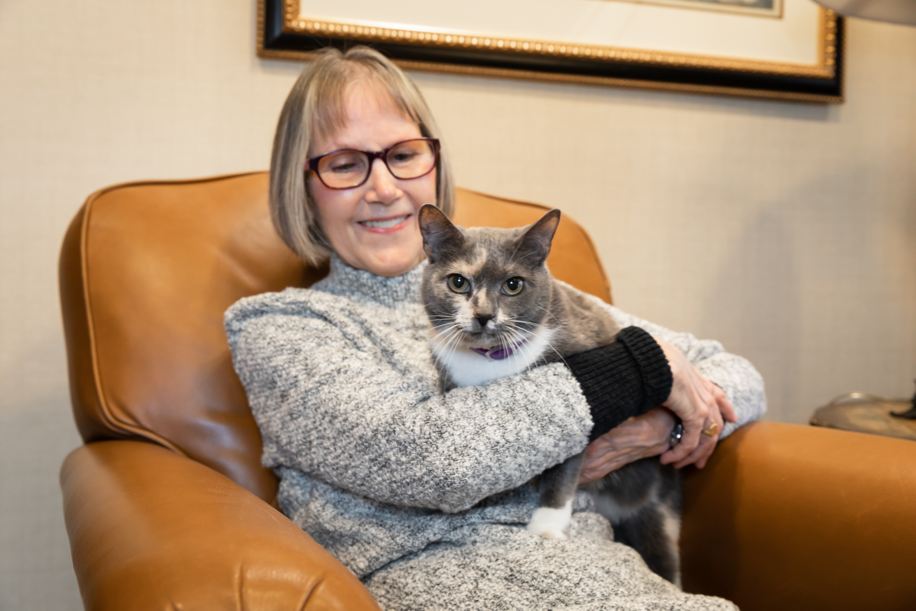 Woman sitting in chair holding gray cat