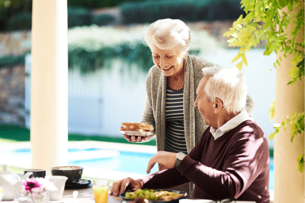 Elderly couple enjoying breakfast on sunny patio
