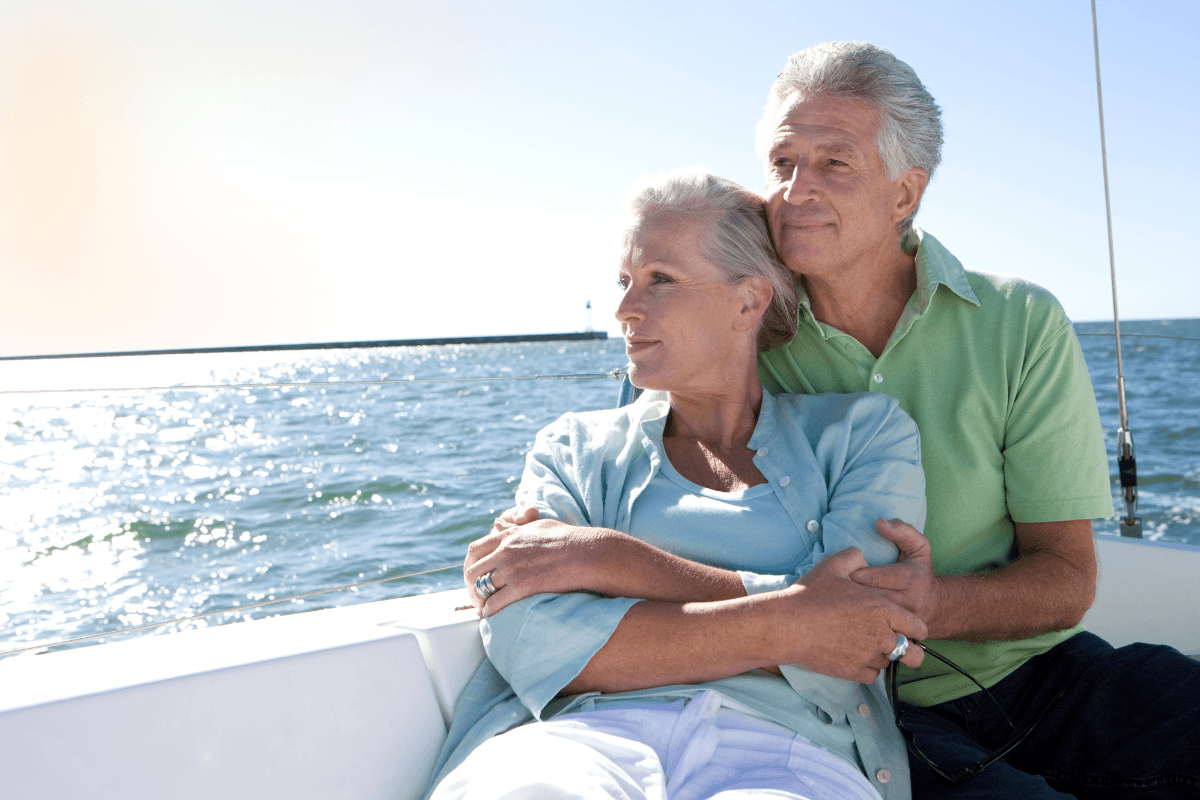 Older couple embracing on sailboat at sea