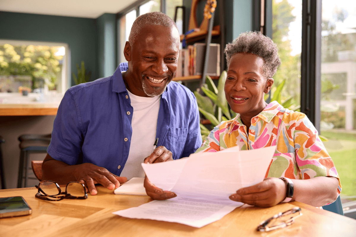 Smiling older couple reviewing papers at home.