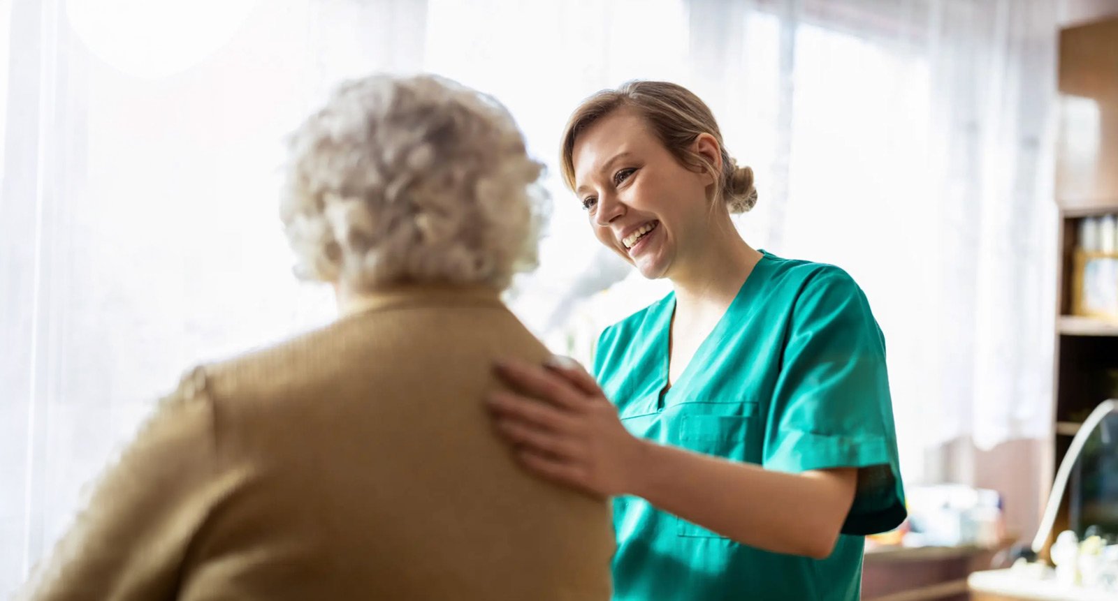 Caregiver comforting elderly woman at home