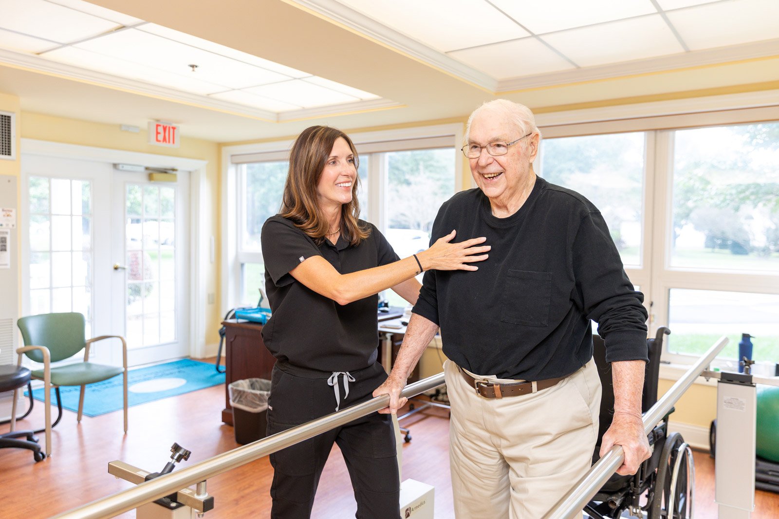 Physical therapist assisting senior man with walking exercises