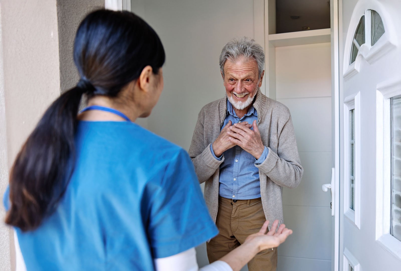 Smiling senior man greeting nurse at doorway