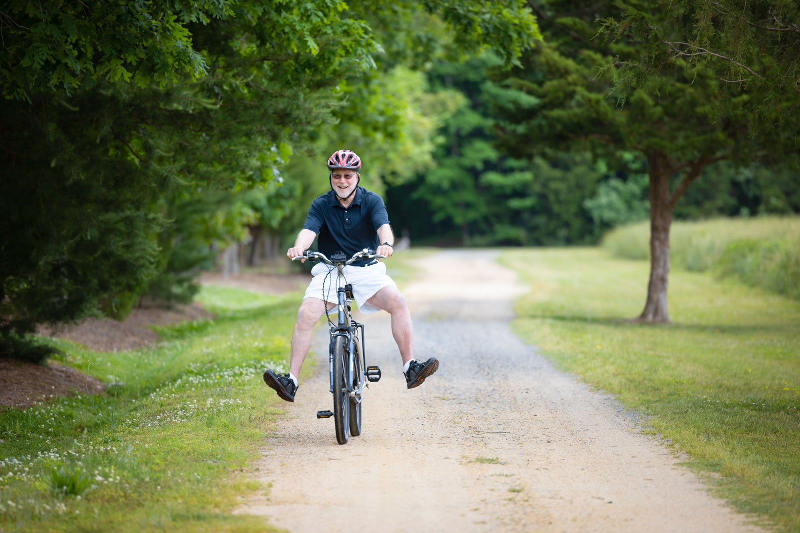 Smiling man cycling on park trail