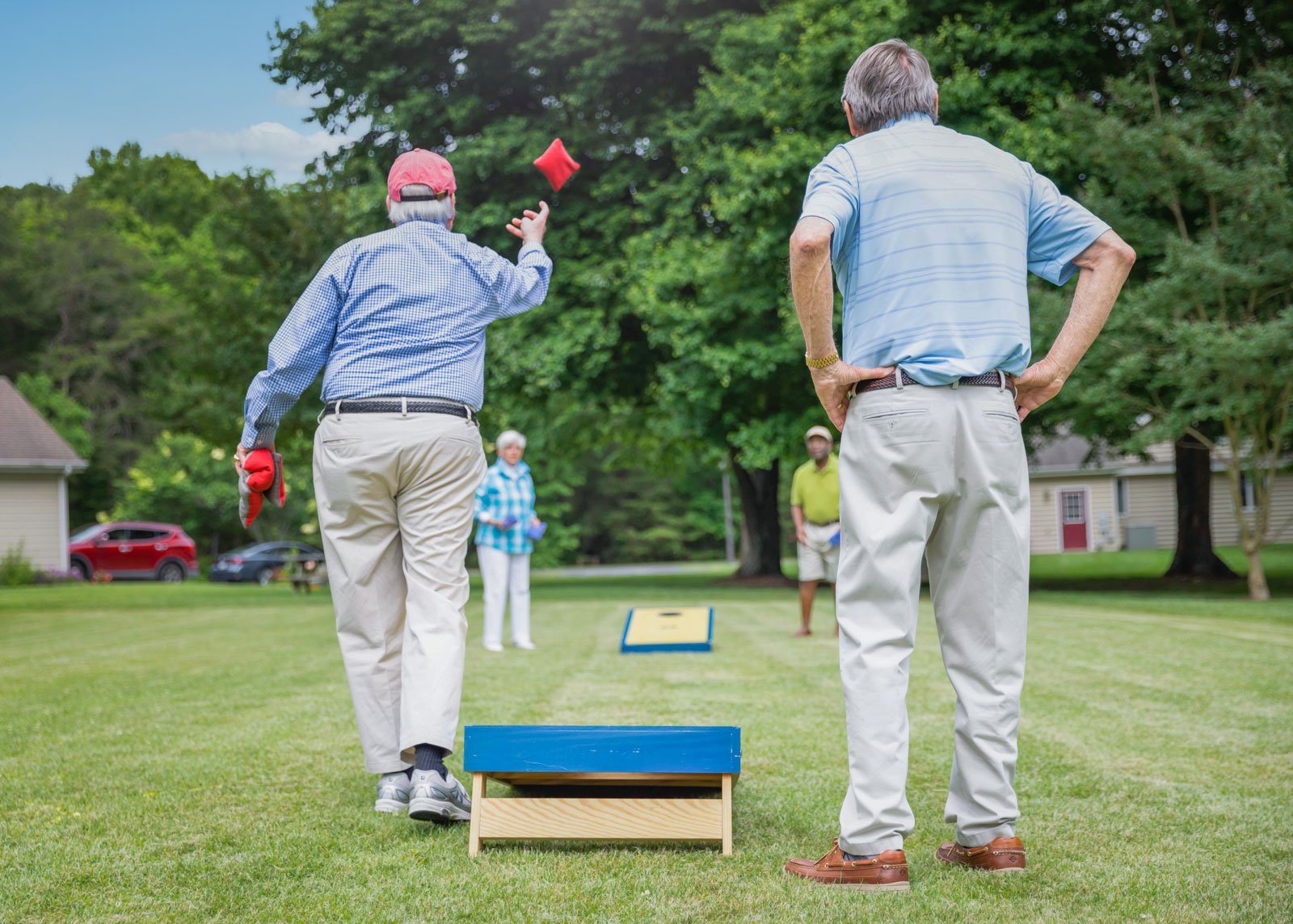 Seniors playing cornhole on grassy lawn