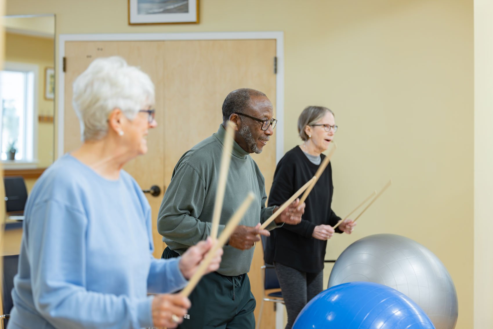 Seniors exercising with drumsticks and stability balls
