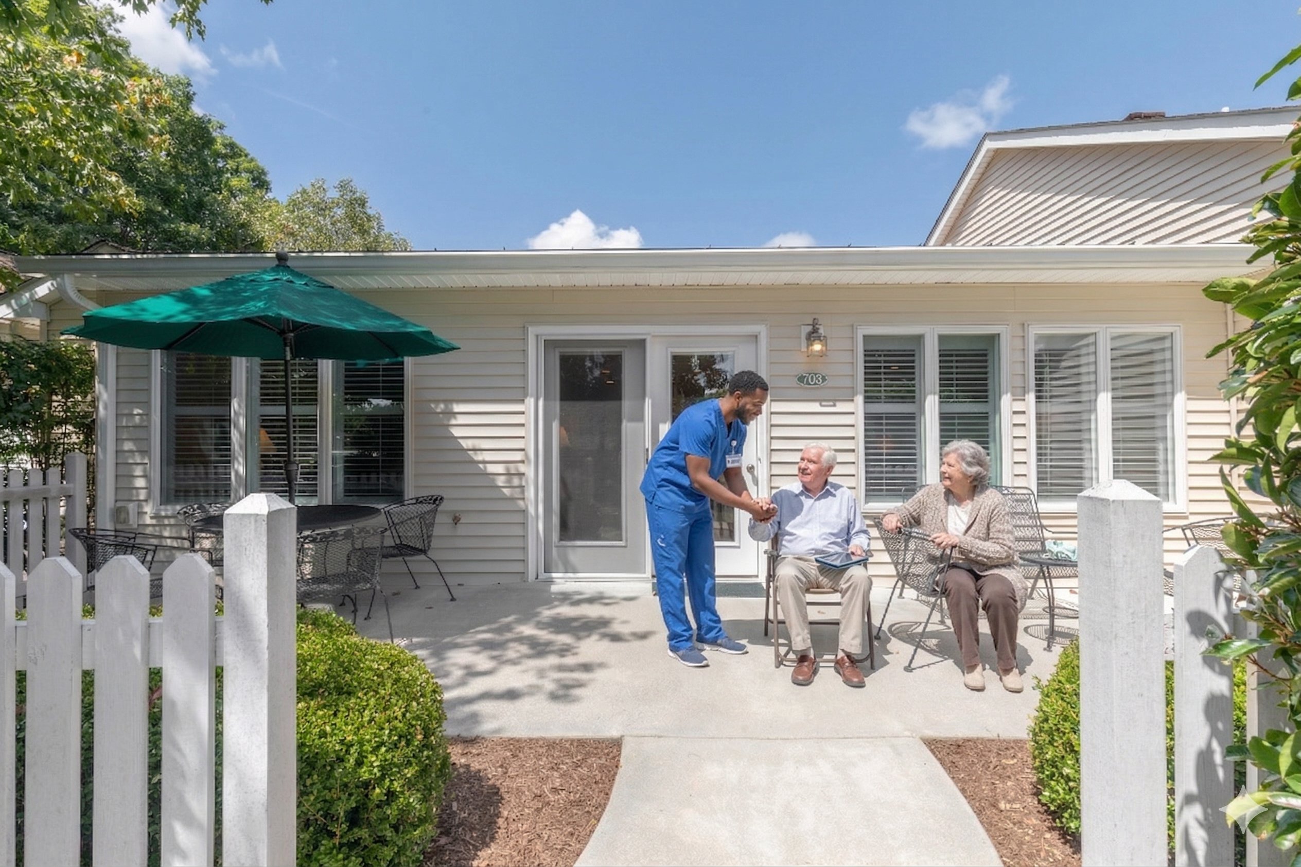 Caregiver greeting elderly couple on sunny porch