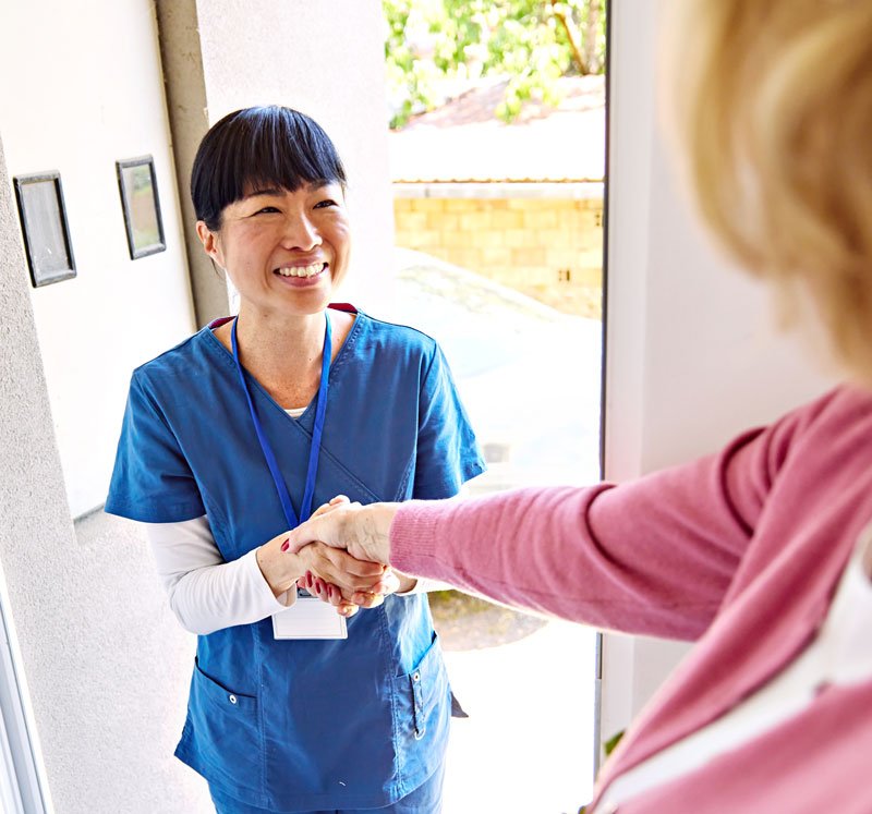 Healthcare worker greeting patient at front door