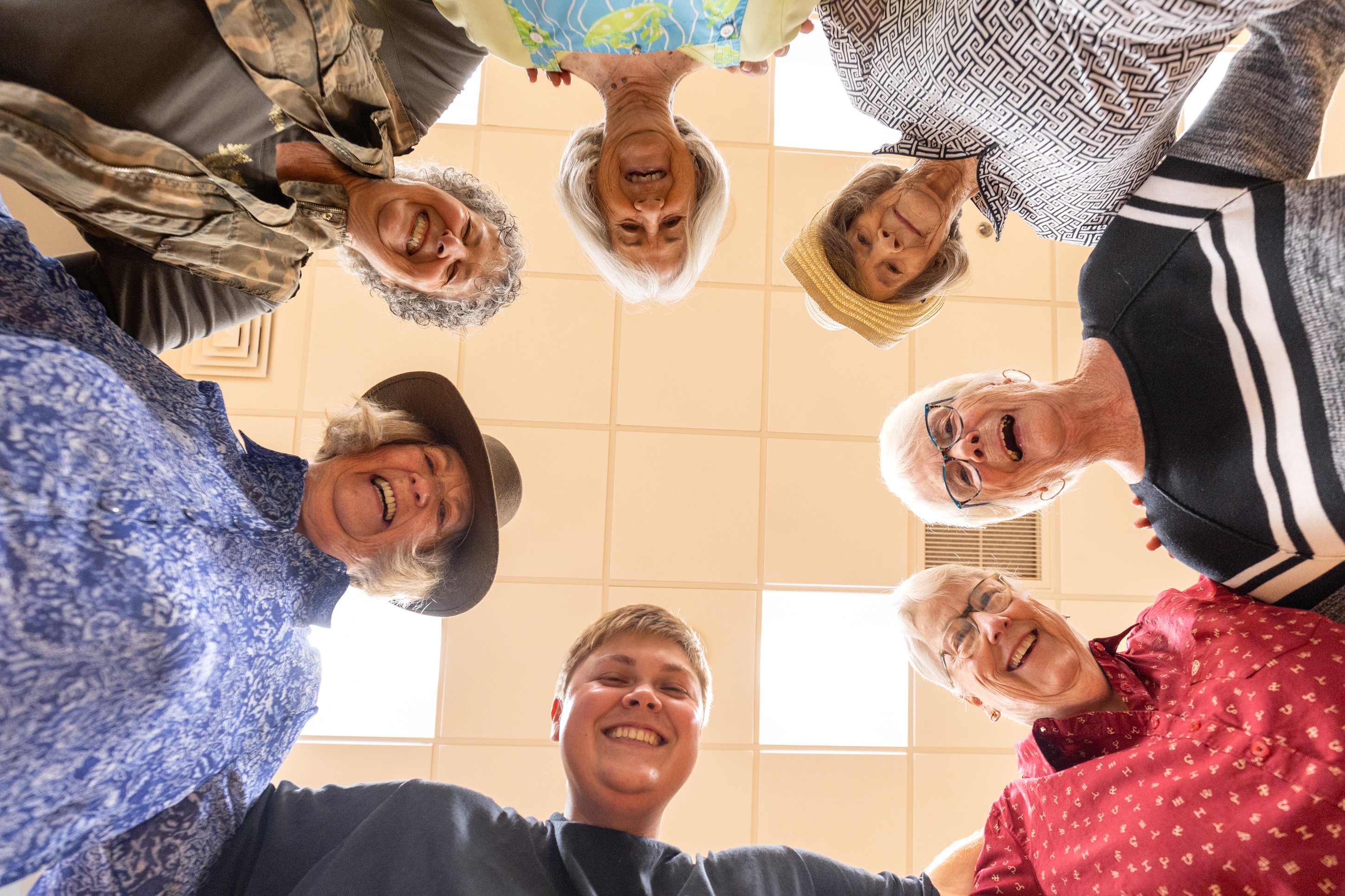 Group of seniors smiling in a circle indoors
