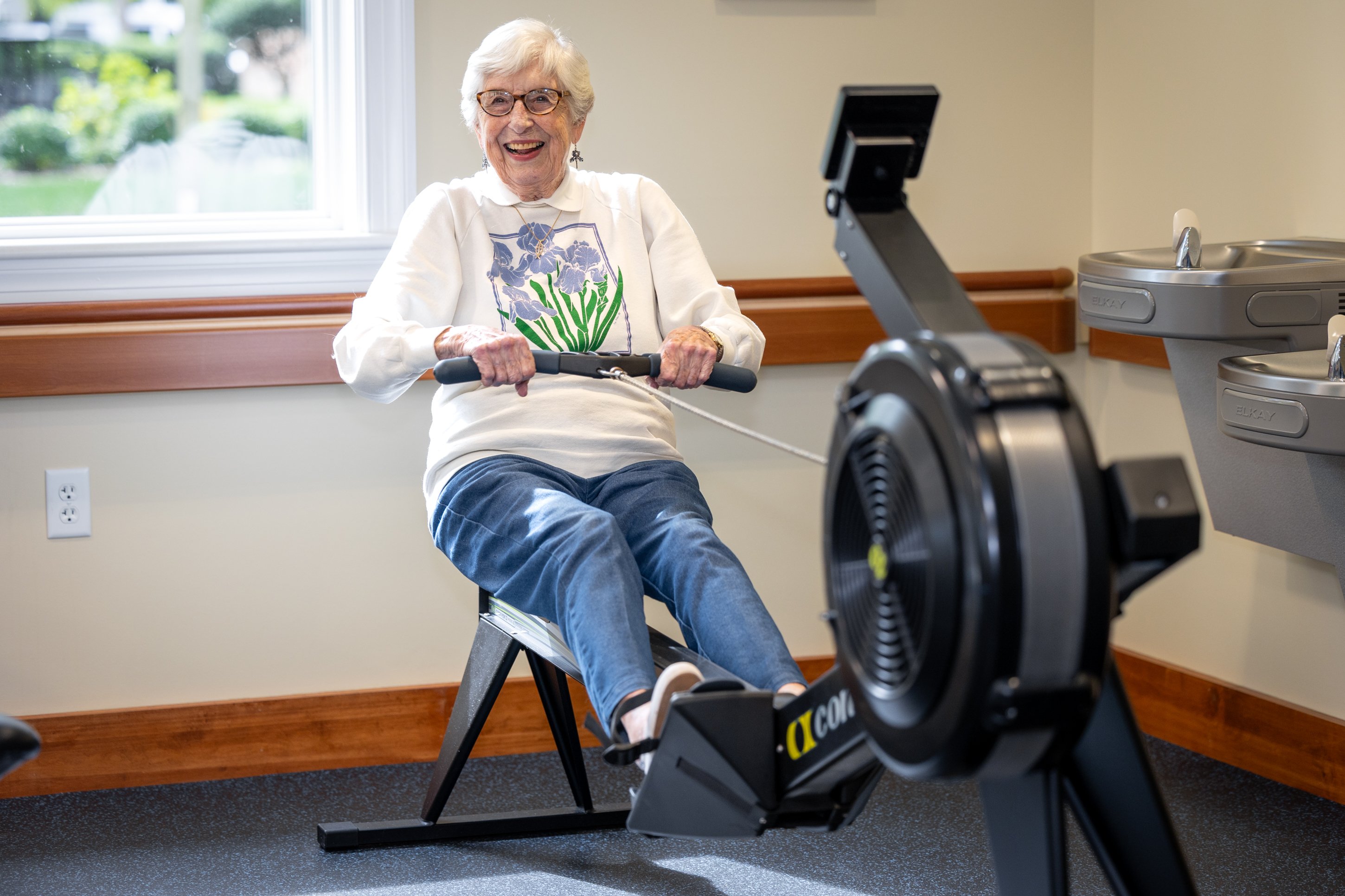 Smiling elderly woman using indoor rowing machine