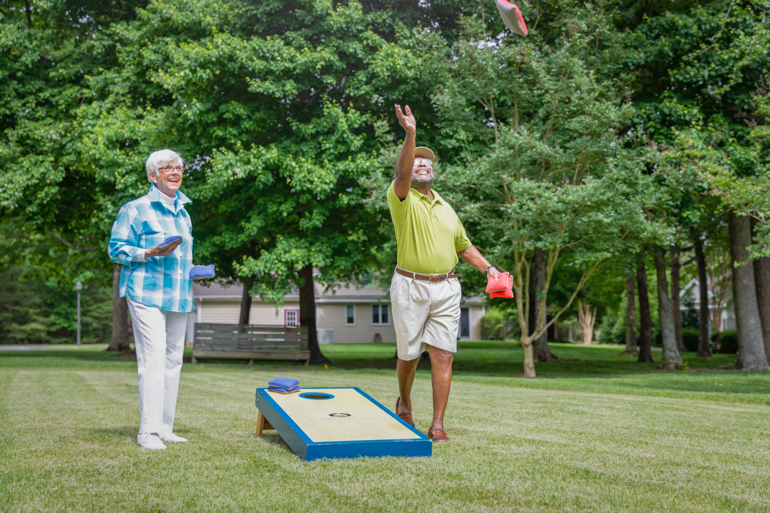 Senior couple playing cornhole in backyard