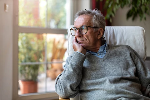 Sad senior man looking out window.