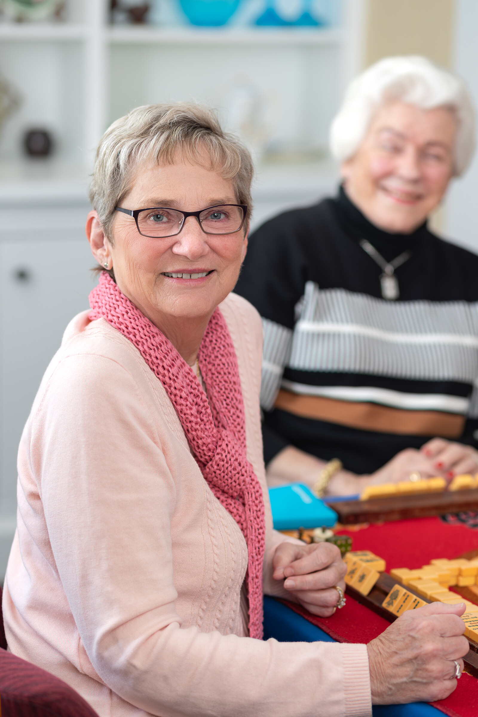 Two senior women playing a board game indoors