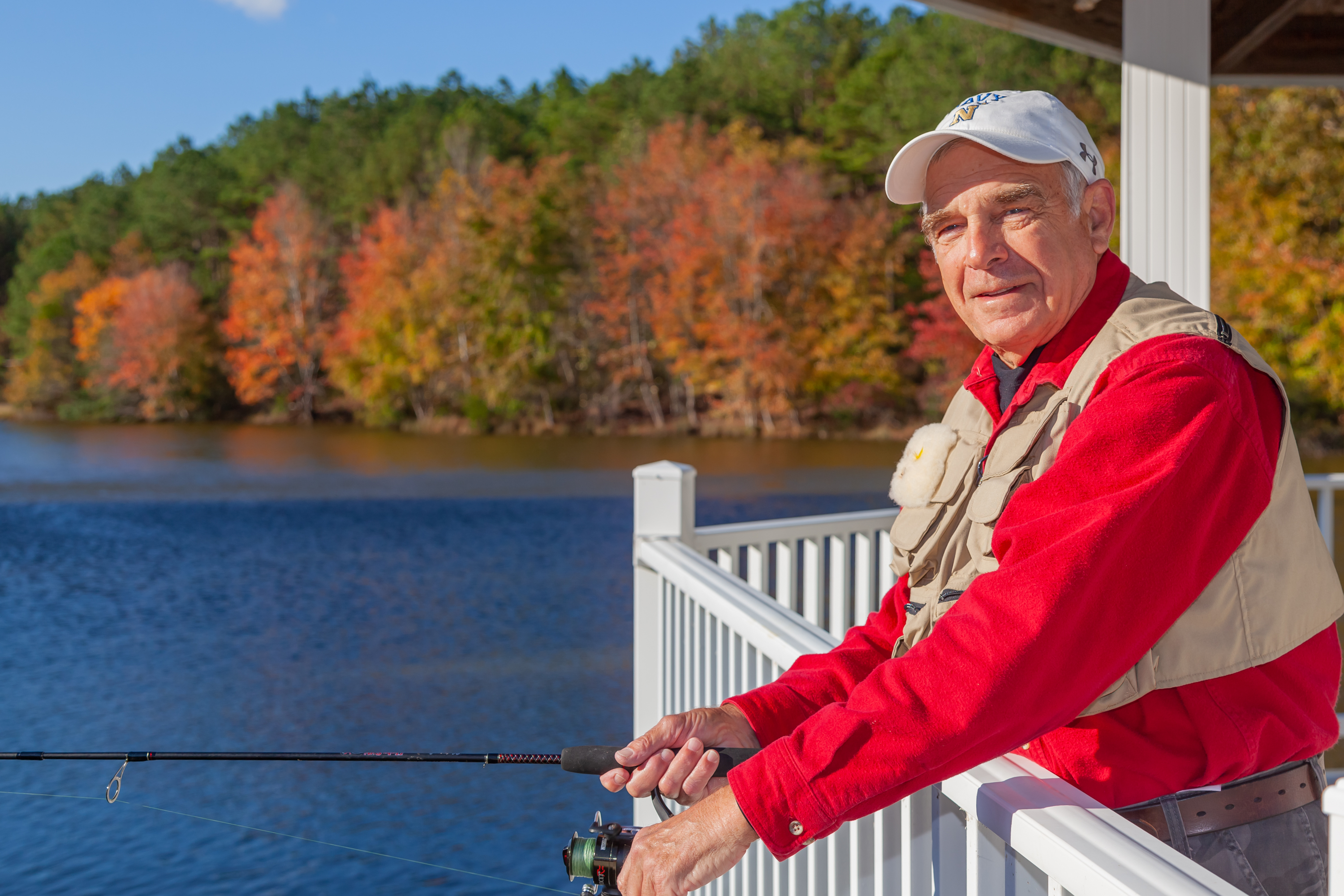 Older man fishing by lake in autumn