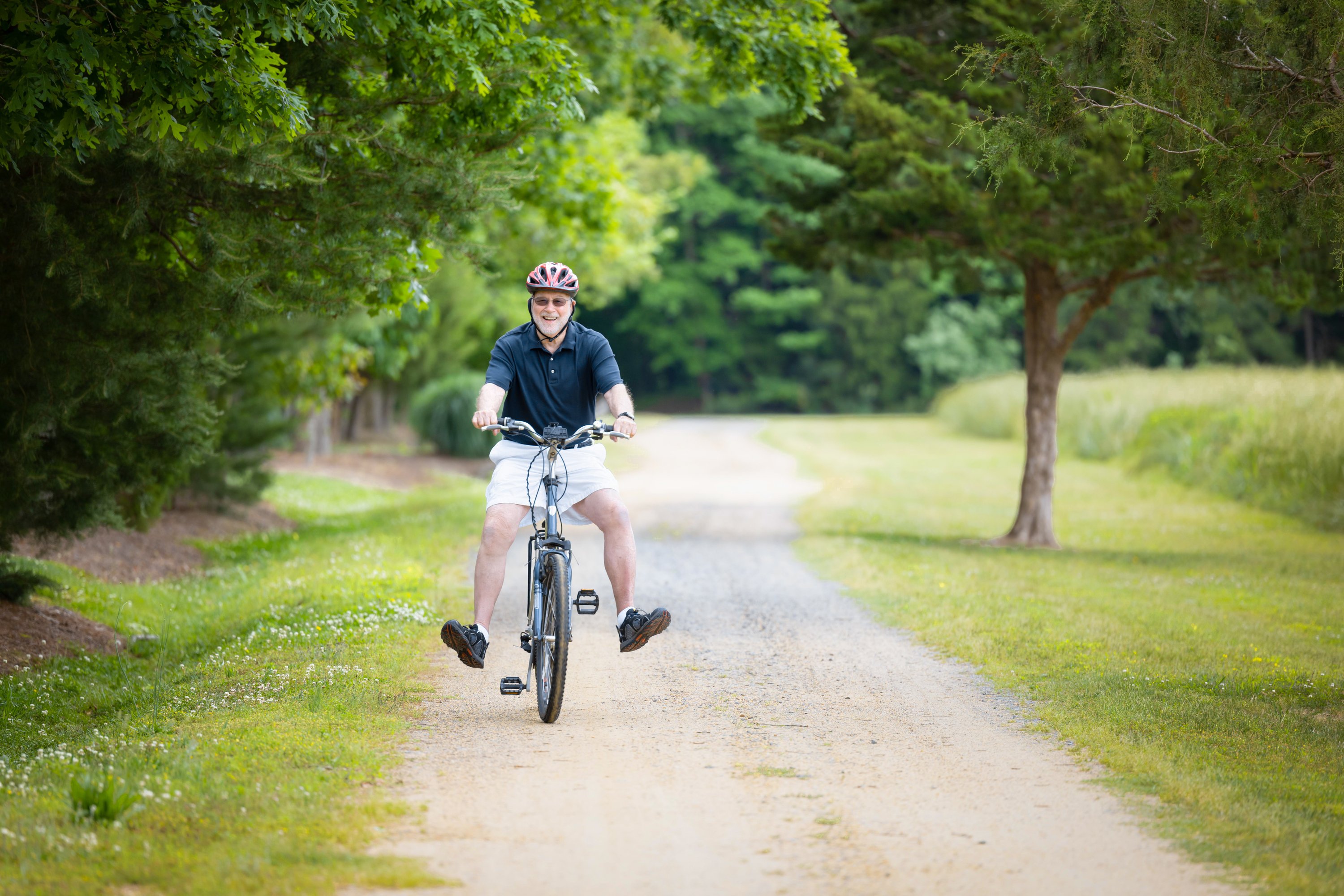 Senior man cycling on tree-lined park trail