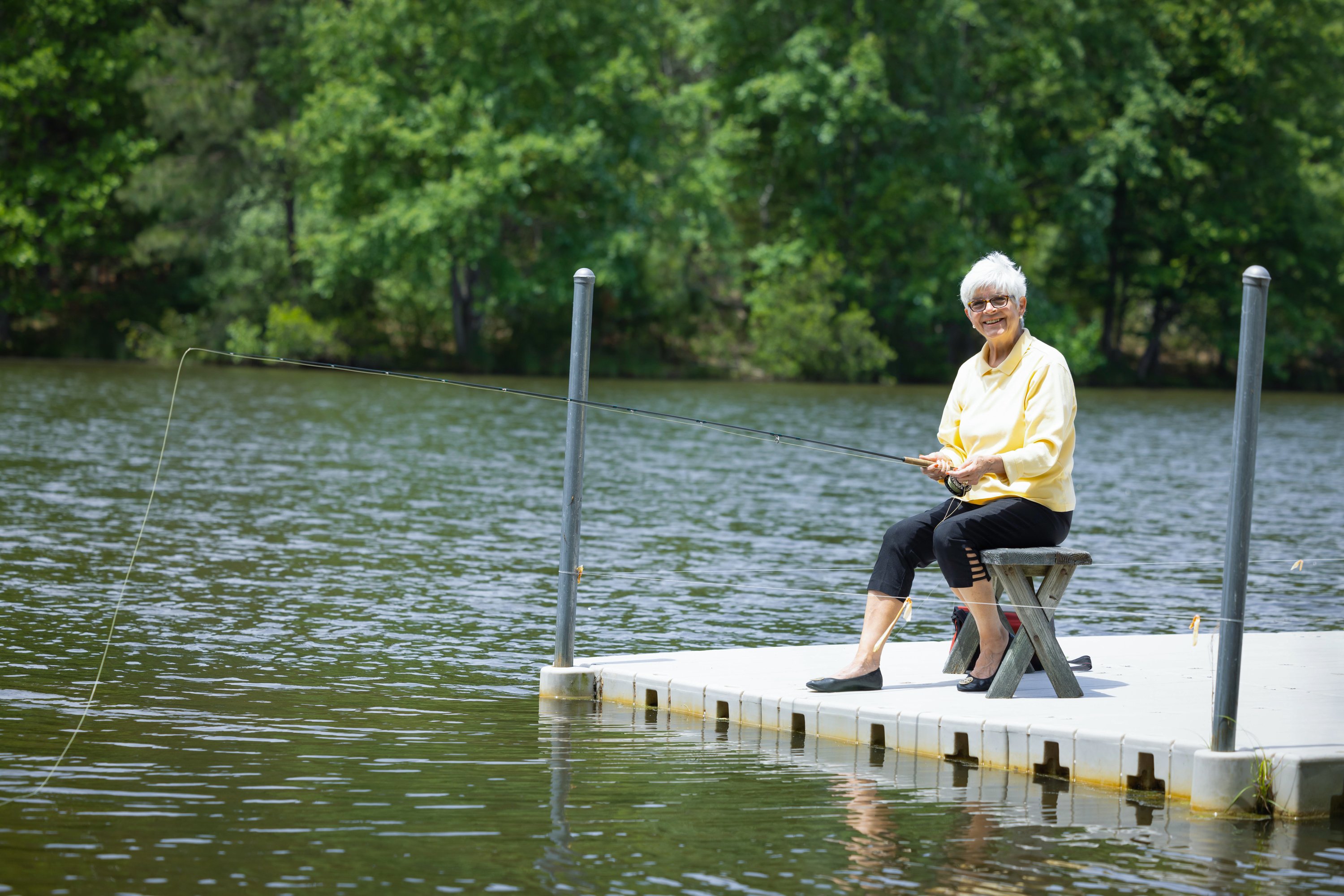 Older woman fishing from lakeside dock